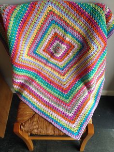 a crocheted blanket is sitting on a wooden chair