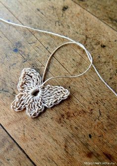 a crocheted butterfly on a wooden floor with the word tadolupn above it