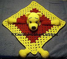 a crocheted bear is laying on top of a yellow and red square blanket