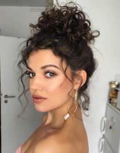 Voluminous curls gathered into an elegant Curly High Bun. Curl Bun Hairstyles, Chopstick Curls Hairstyles, Curly Hair High Bun, High Bun Curly Hair, Curly Top Knot Bun, Curly High Bun, High Curly Bun, Big Bun Hairstyles, Elegant High Bun