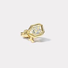 a yellow gold ring with an octagonal cut diamond set in the center, on a white background