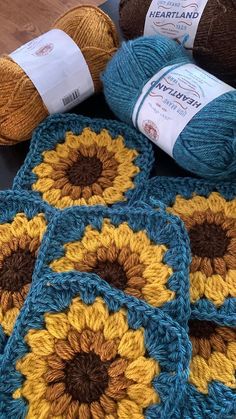 crocheted sunflowers are sitting on the floor next to balls of yarn