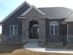 a house that is made out of stone and has a brown front door with two windows