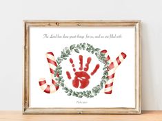 a christmas card with a handprint and candy canes on the front, in a frame