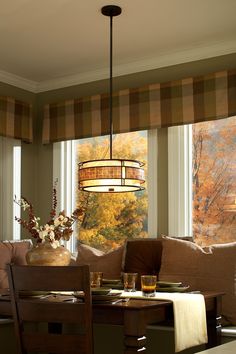 a dining room table and chairs in front of a window with fall foliage on the windowsill