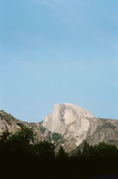 an airplane flying over the top of a large mountain with trees on it's sides