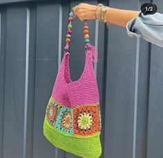 a woman holding a crocheted bag with beads on it's handles and handle