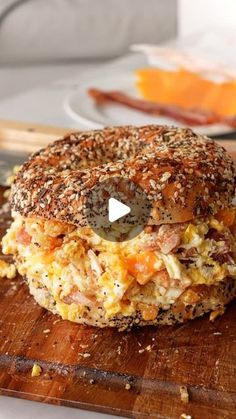 a bagel sandwich sitting on top of a wooden cutting board