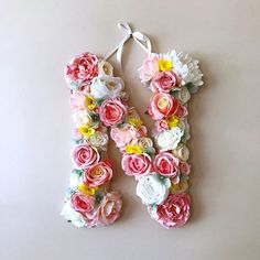 the letter n made out of flowers is hanging from a string on a white wall