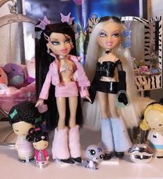 two dolls are standing next to each other in front of a wall with pictures on it