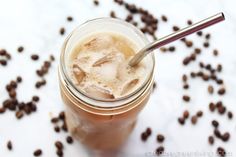 an iced drink in a mason jar surrounded by coffee beans