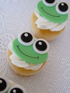 two cupcakes decorated with green and white frosting, eyes and noses on top of each other