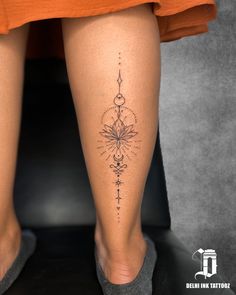 a woman's legs with a tattoo on the bottom of her leg and an orange dress underneath