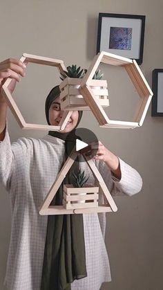 a woman is holding up some wooden structures