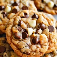 chocolate chip cookies are piled on top of each other with white and brown chips in the middle