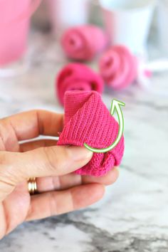 a person holding a pink knitted object with an arrow on it's side