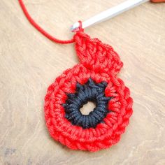 a crocheted red and black object on a table with a pair of scissors