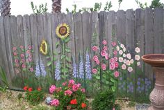 a fence with flowers painted on it and a birdbath in the foreground