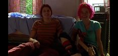 two women sitting on a couch with pink hair