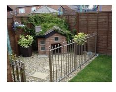 a dog house in the middle of a yard with a fence and green grass around it