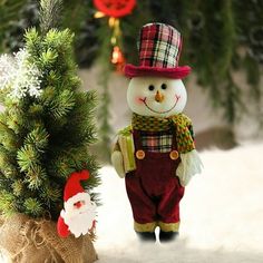 a small snowman standing next to a christmas tree