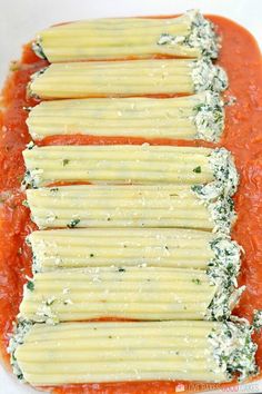 several pieces of ravioli on top of sauce in a white dish with parmesan cheese