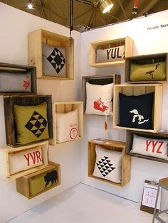 several wooden crates with decorative pillows on them in a room filled with white walls and flooring