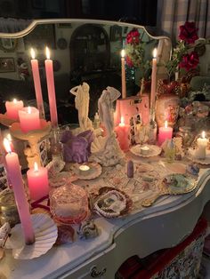 a table topped with lots of candles next to a dresser covered in dishes and other items