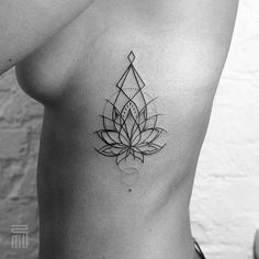 a black and white photo of a woman's chest with a lotus tattoo on it