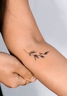 a woman's arm with a small tattoo design on the left side of her arm