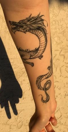 a woman's leg with a dragon tattoo on it and a shadow behind her