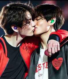 two young men kissing each other while wearing earbud's on their ears