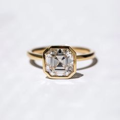 a yellow diamond ring sitting on top of a white marble slabd surface, with the center stone surrounded by small diamonds