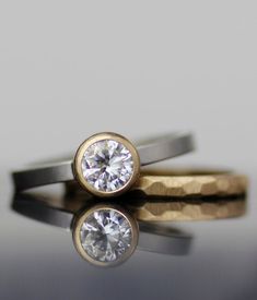 two gold and silver rings with a diamond on the top one has a single stone in it