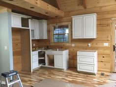 an unfinished kitchen with white cabinets and wood floors