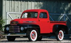 an old red truck parked in front of a barn