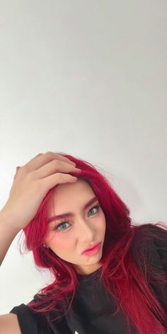 a woman with red hair is posing for the camera and has her hands on her head