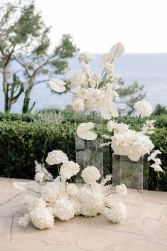 white flowers are arranged in square vases on the ground