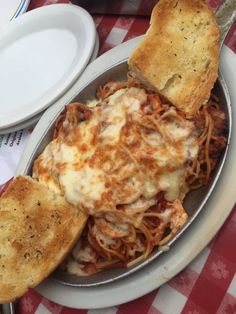 a plate of spaghetti and bread on a red and white checkered tablecloth with silverware