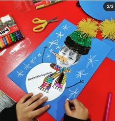 a child's hand is drawing a snowman with colored pencils