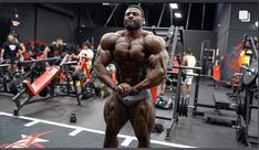 a bodybuilding man standing in the middle of a gym