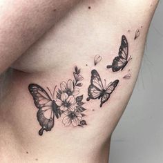 a woman's stomach with three butterflies and flowers on the side, all around her