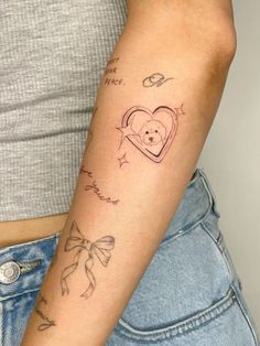 a woman's arm with tattoos on it and a heart in the shape of a bear