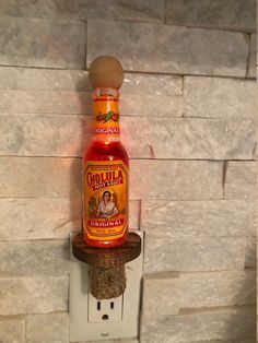 a bottle of liquor sitting on top of a wooden shelf next to a light switch