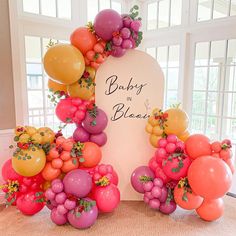 balloons and flowers are arranged around a sign for a baby's first birthday party