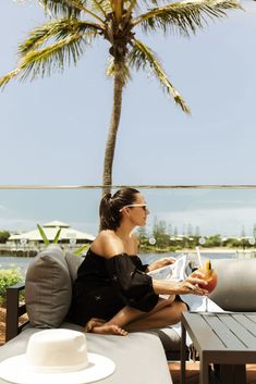 a woman sitting on top of a couch next to a palm tree