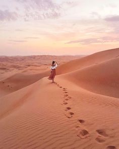 a person walking in the desert with footprints coming out of the sand to their left