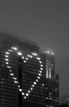 black and white photograph of buildings in the city at night with heart shaped lights on them