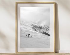 a black and white photo of snow covered mountains in the distance with a wooden frame