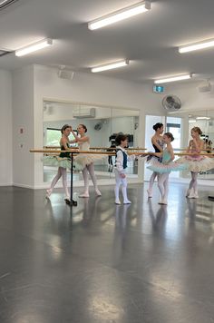 several young ballerinas are practicing their moves in the dance studio with mirrors behind them